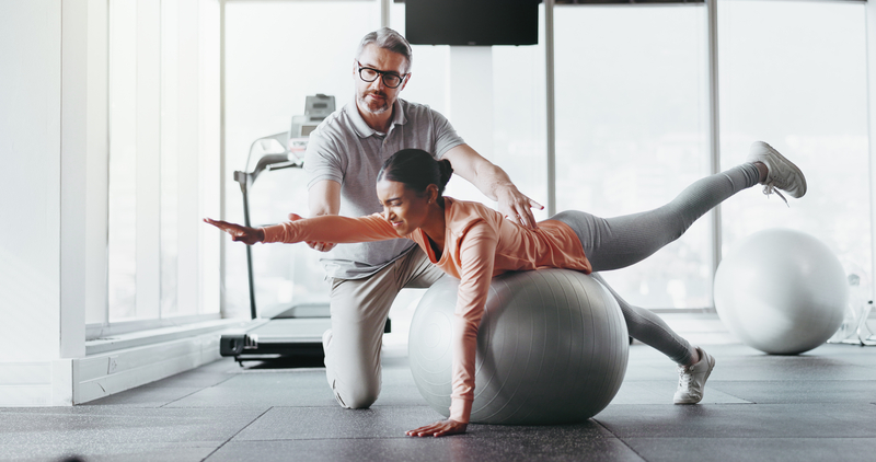 personal trainer correcting form, swiss ball